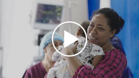 Video thumbnail showing a mother smiling and hugging her baby.