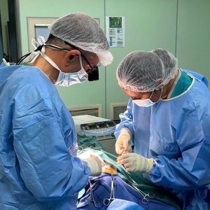 Two surgeons, a man and a woman, work together to complete a procedure.