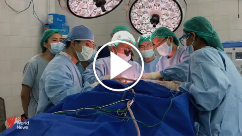 Video thumbnail showing a surgical team performing a procedure on an unseen patient with a play button on top.