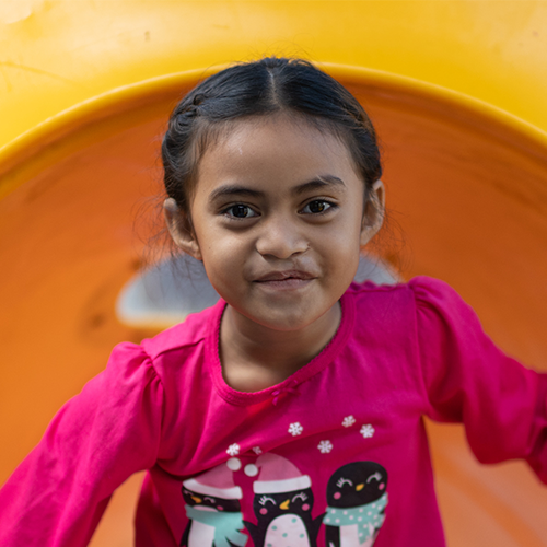 A young girl with a barely perceptible scar on her top lip smiles for the camera.