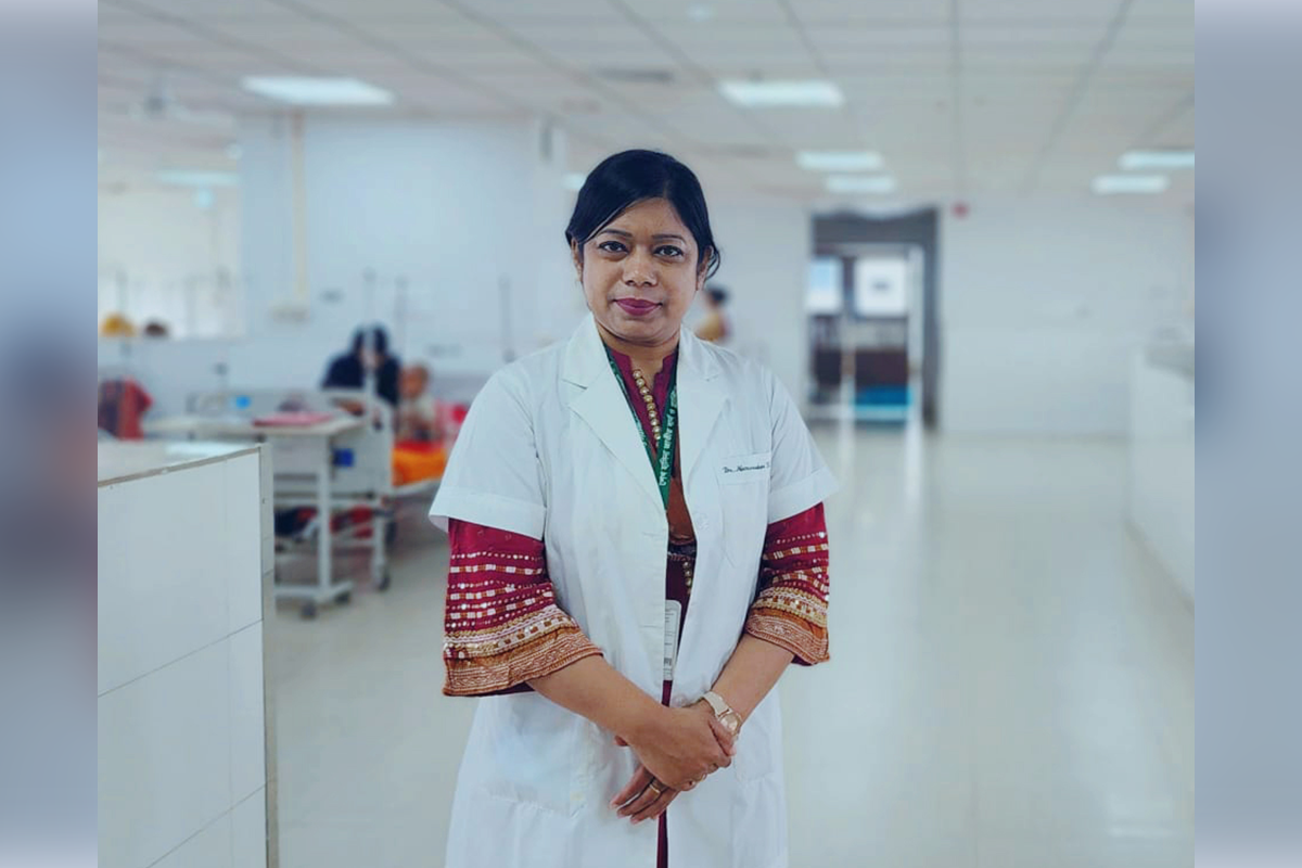Photo of Dr Begum in a white cost in a hospital ward.