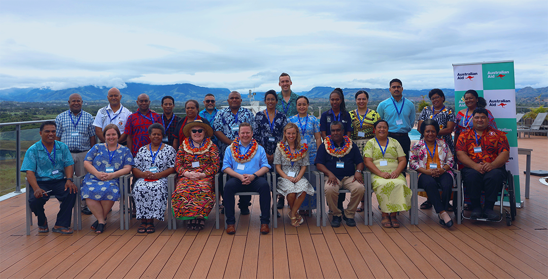 A large group of people gather outside to take a photo.