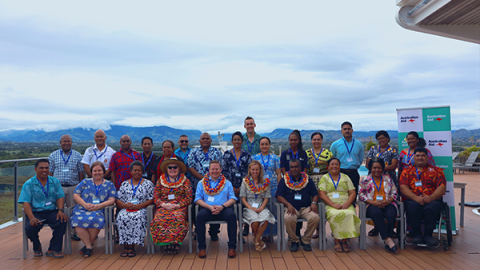 A large group of people gather outside to take a photo.