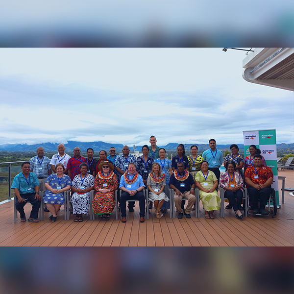 A large group of people gather outside to take a photo.