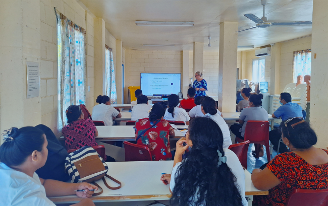 A group of people watch a presentation.