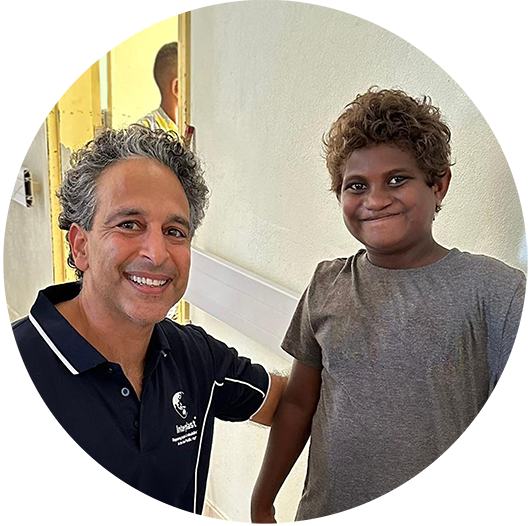 A young boy smiles for a photo with an Interplast volunteer.