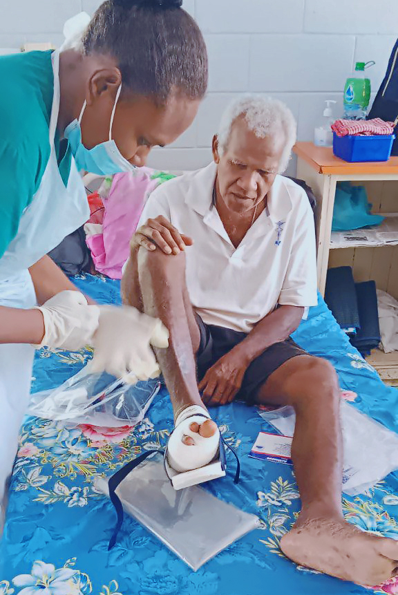 A nurse bandages foot of a man on a hospital bed.