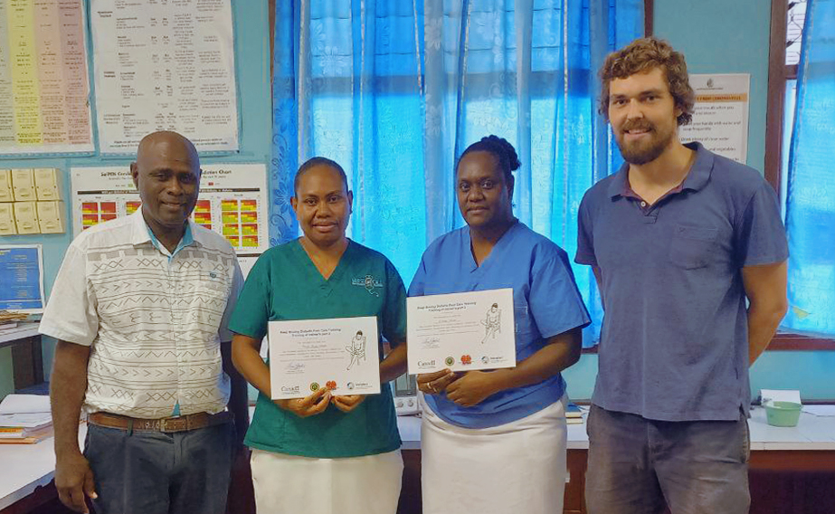 Four people smile for the camera; two hold up certificates.