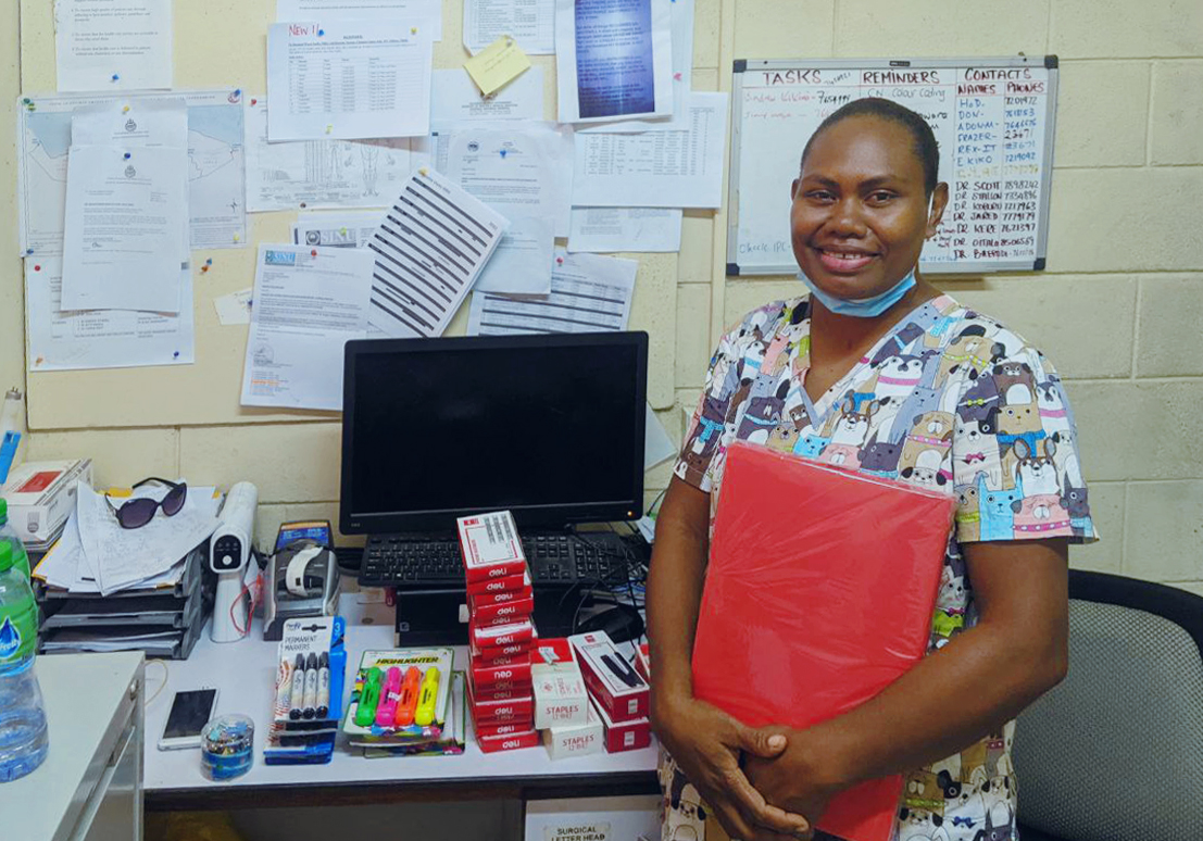 A woman stands next to boxes of supplies.