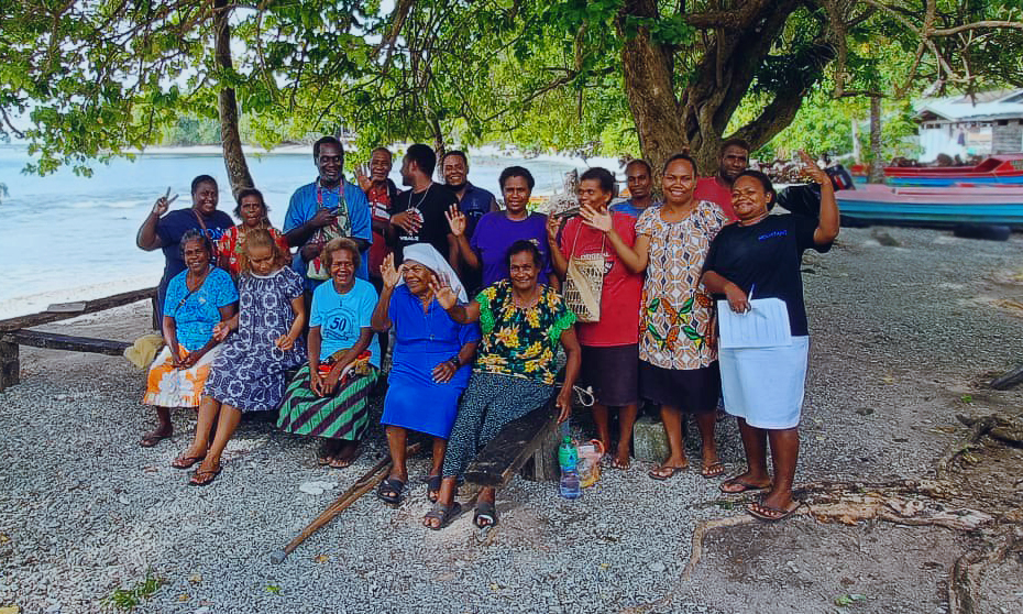 A group of people stand on the beach and smile.