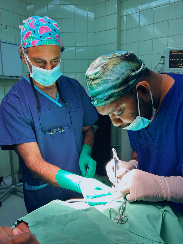 Two surgeons work together to perform surgery on an unseen patient.