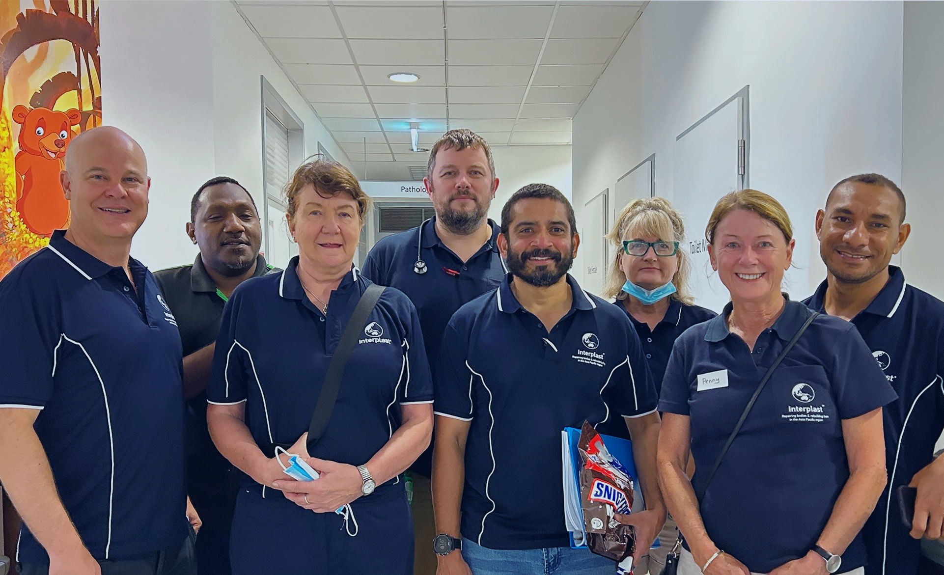 Eight people, seven wearing Interplast polo shirts, smile for a photo.