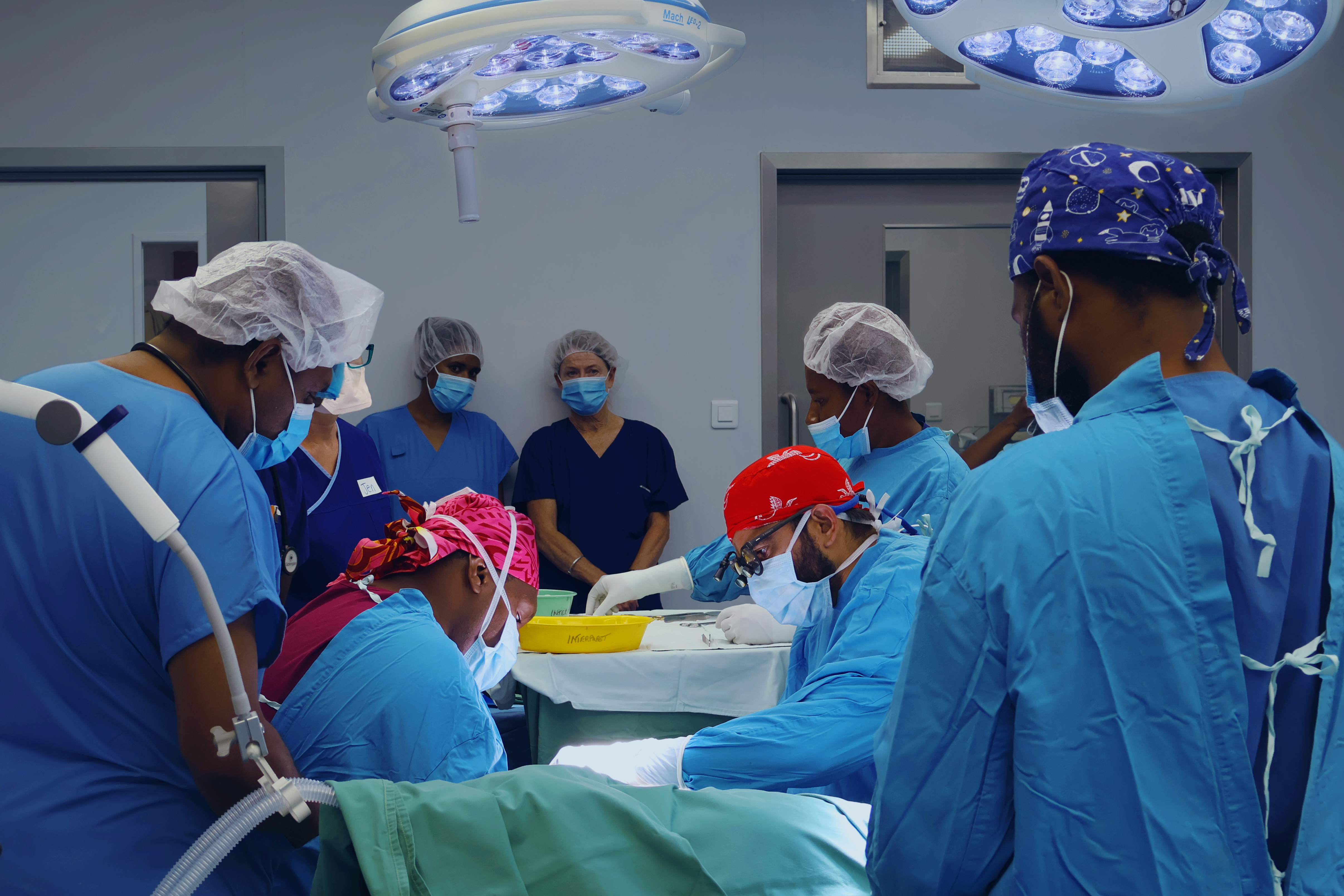 A group of people in the operating theatre, supporting surgery on an unseen patient.