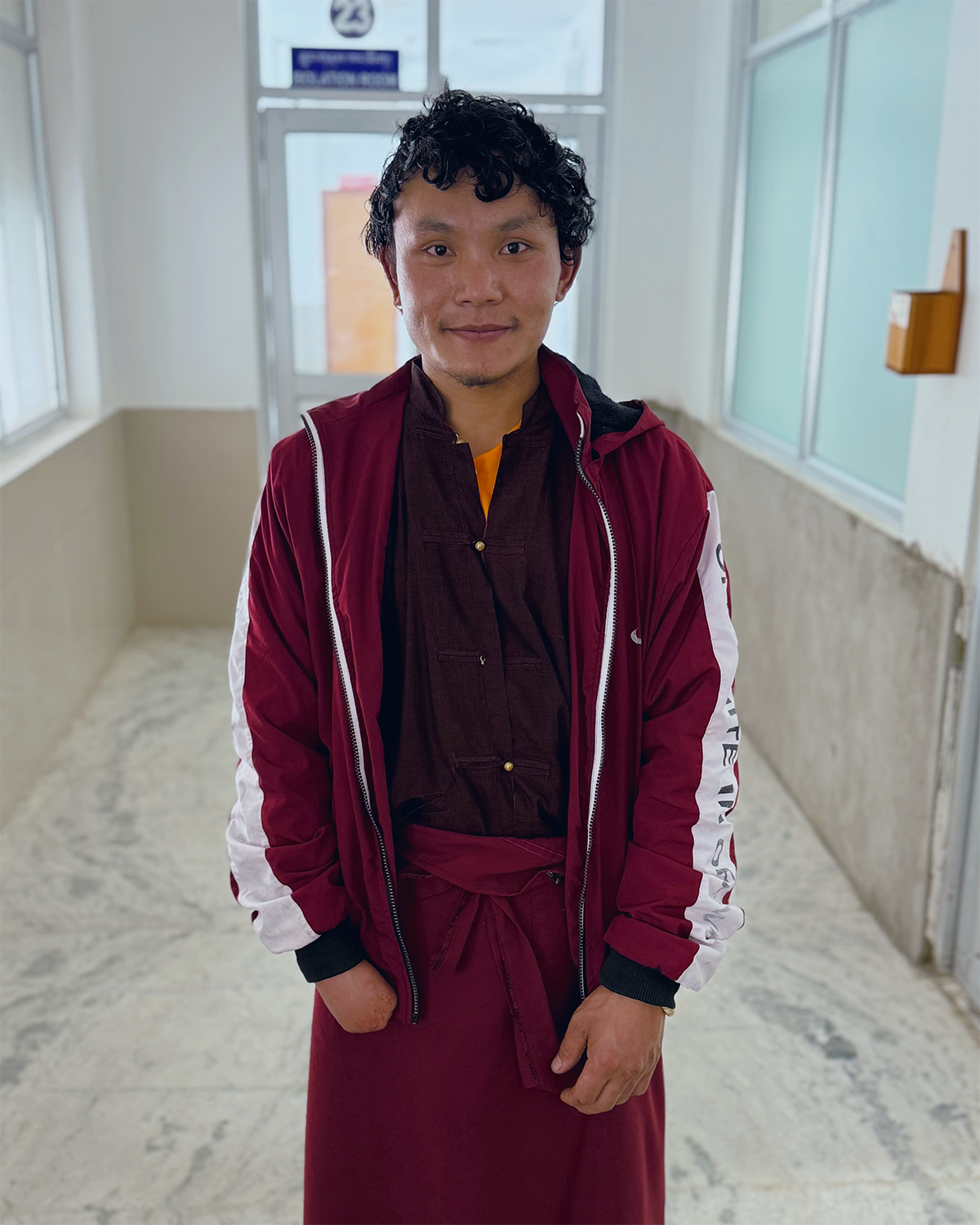 A young man with significant scarring of his right hand smiles for the camera.