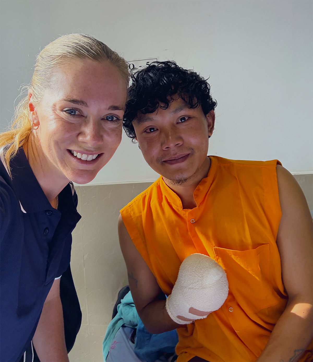 A man with a bandaged hand and a woman smile for a photo together.