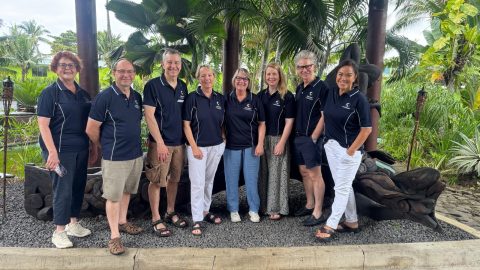A group of 8 people stand smiling at the camera